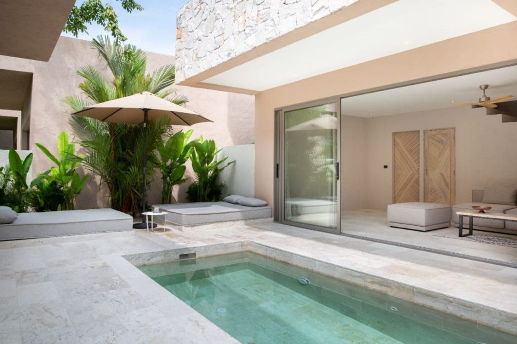 A private pool beside an open bedroom, palms behind it